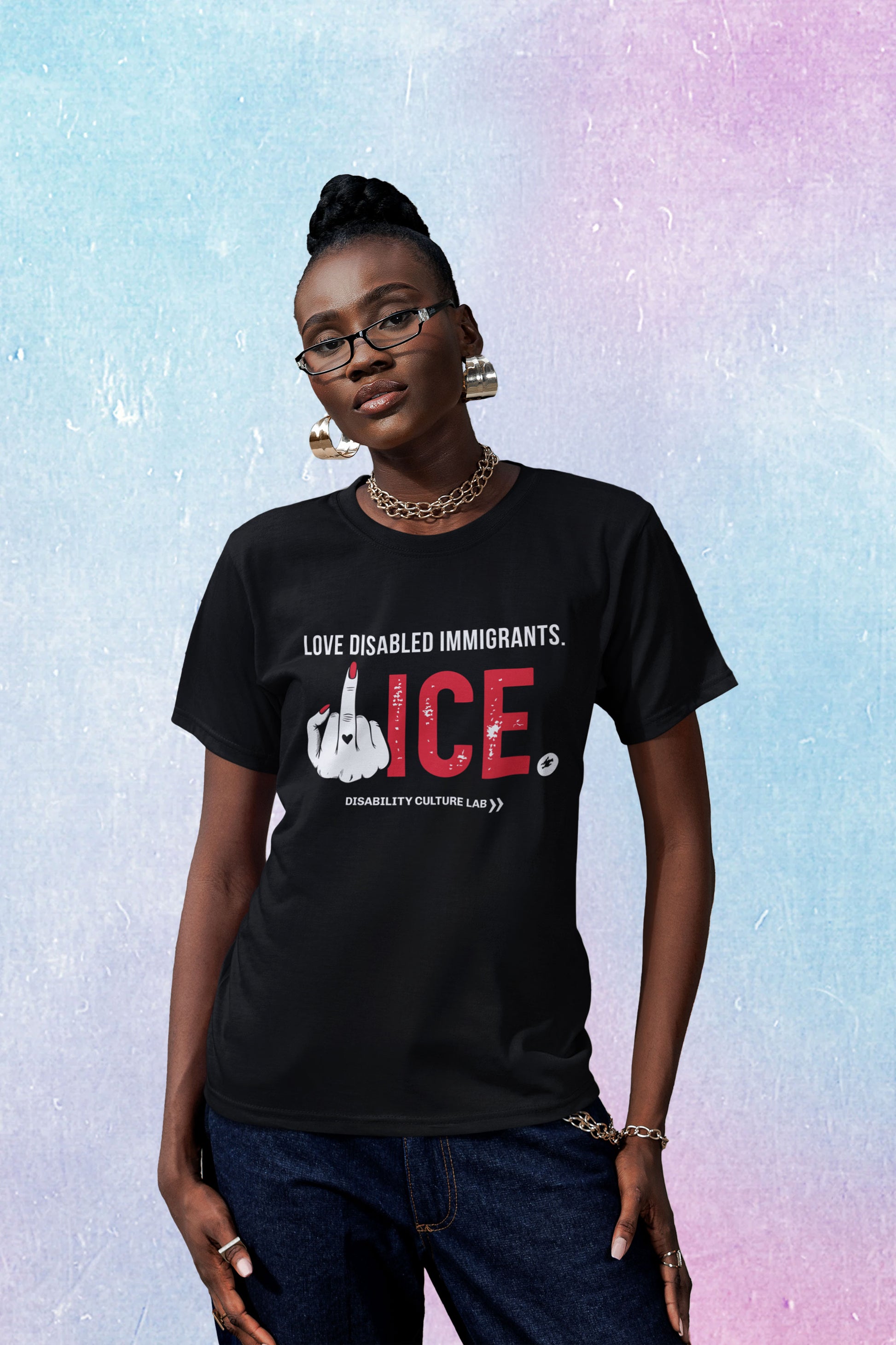 A Black person with a top knot looks at the camera. They are wearing black glasses, gold jewlery, dark blue jeans, and a black t-shirt that reads "Love Disabled Immigrants" in white text. Below is a hand with red nails and a black heart on the middle finger flipping the middle finger, and large textured text that reads "ICE," with "ICE" in red and the period in white. All together, the message can be read "Love Disabled Immigrants. Fuck Ice." White Disability Culture Lab logo.