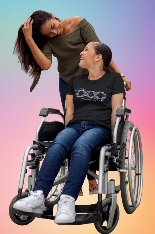 Two people, one with brown skin and long hair, the other white and sitting in a wheelchair wearing blue jeans, white sneakers, and a black short sleeve T-shirt with a pink and blue four-line loop, like an infinity sign with an extra loop added to it. Text reads, "Interdependence Is Revolutionary" and starts at the top left of the diagram, weaves into the center of the diagram and then ends at the bottom right. Below is the white Disability Culture Lab logo.