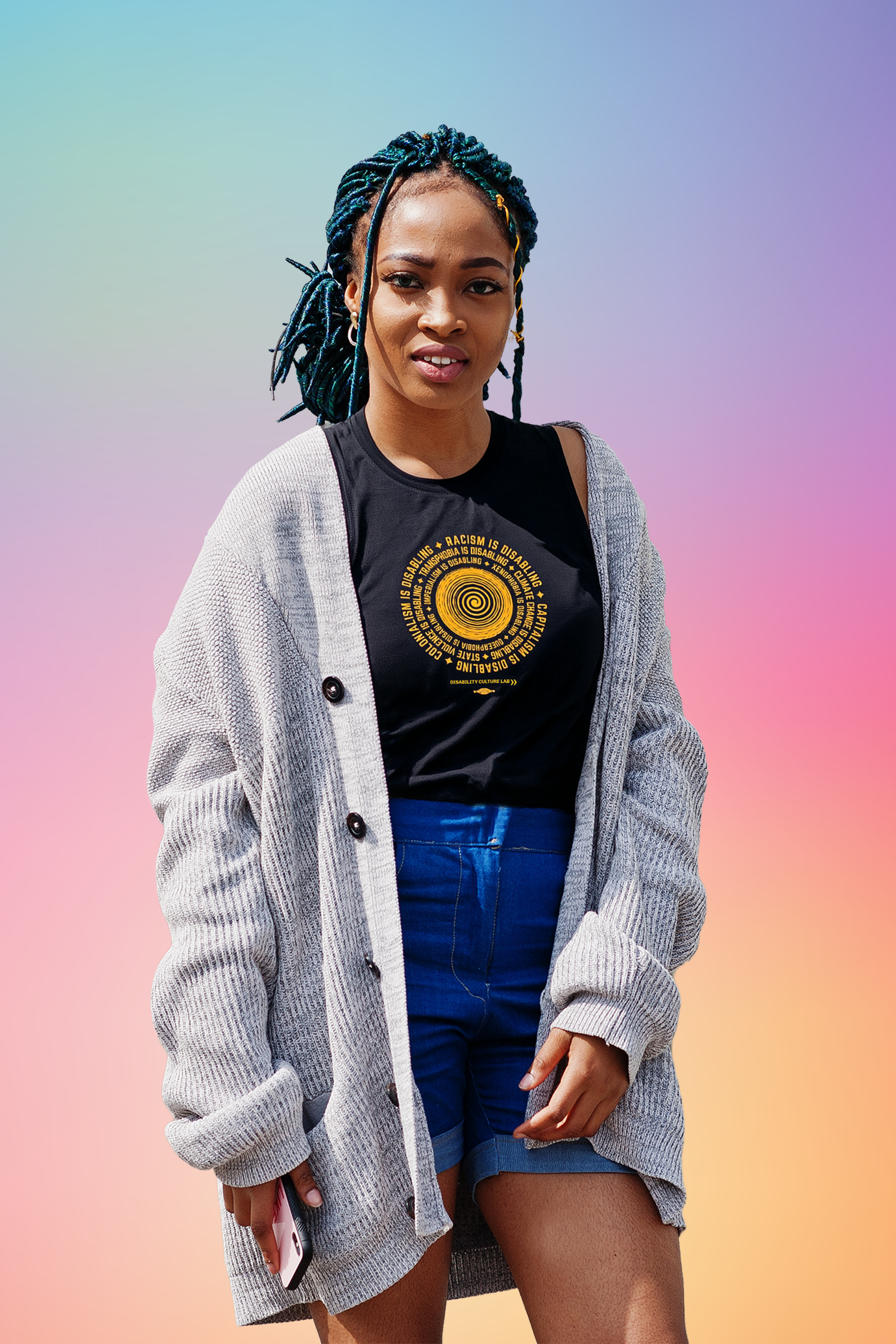 A Black person with long dark green faux locs. They are wearing the black "Oppression is Disabling" muscle tank, blue jean shorts, and a gray cardigan The muscle tank has a circular design in the middle. In the center of the design there is an orange spiral, with an orange text surrounding it in a circle that reads "Racism is disabling. Capitalism is disabling. Colonialism is disabling. Transphobia is disabling. Climate change is disabling. State violence is disabling," and more. DCL logo is below.