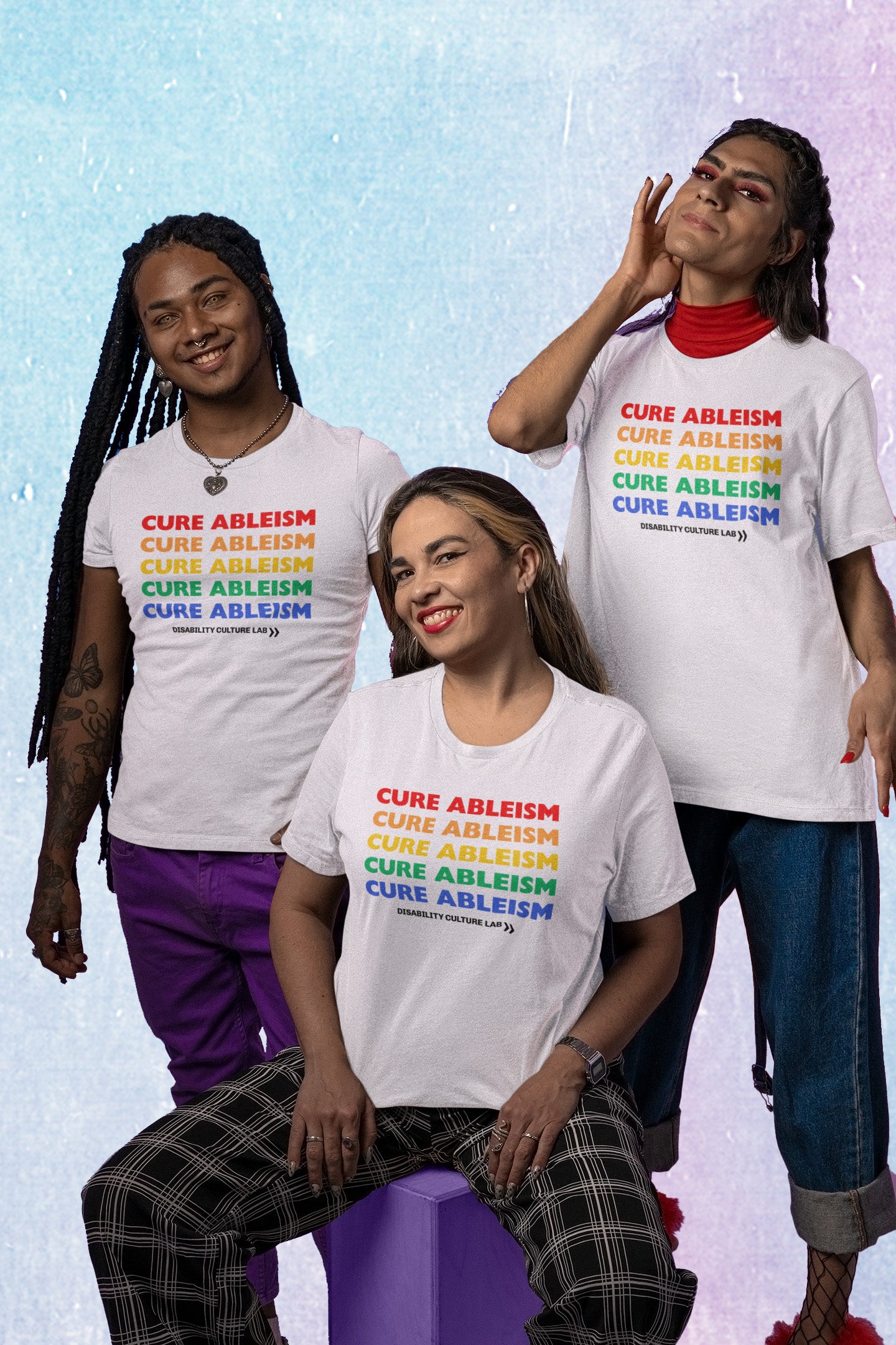 A picture of three Black and Brown queer folks in white tshirts that read “Cure Ableism” written five times in rainbow pride colors. 