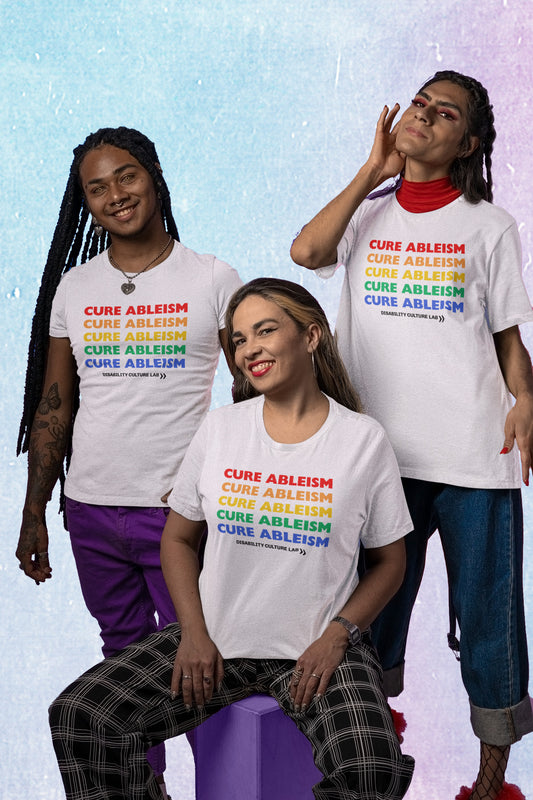 A picture of three Black and Brown queer folks in white tshirts that read “Cure Ableism” written five times in rainbow pride colors. 