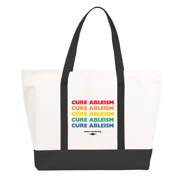 A large white tote bag with black handles and bottom that reads "Cure Ableism" five times in red, orange, yellow, green, and blue, and the white Disability Culture Lab logo. 