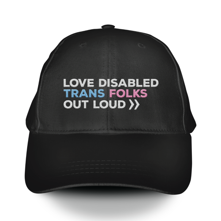 A black embroidered hat that reads, "Love Disabled Trans Folks Out Loud." The text is in the colors of the trans flag, with "Love Disabled" in white, "Trans" in light blue, "Folks" in light pink, and "Out Loud" in white. Next to the words "Out Loud" are two white arrows, from the Disability Culture Lab logo.
